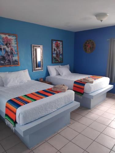 two beds in a room with blue walls at Hotel Casa Victoria in Puerto Peñasco