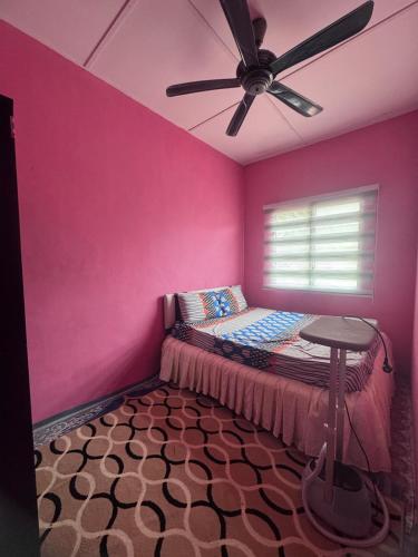 a pink bedroom with a bed and a ceiling fan at Homestay Pangkor Ann in Pangkor