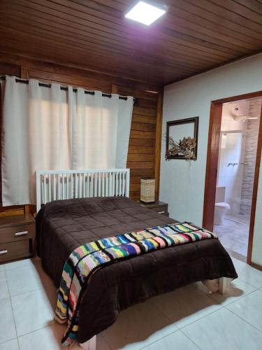 a bedroom with a bed with a blanket on it at Eco Cabana Mantiqueira in Queimada