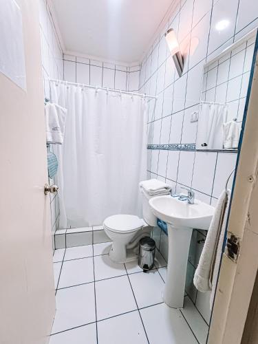 a white bathroom with a toilet and a sink at Hostal del Rio Talca in Talca