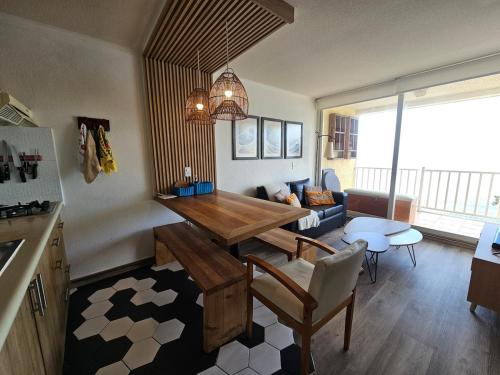 a kitchen and living room with a table and a couch at Departamento frente al mar, con piscinas y vista panorámica in Puchuncaví