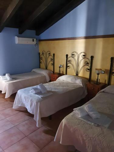 a room with three beds and a blue wall at Fuente Los Avellanos in Villanueva del Arzobispo