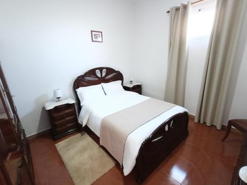 a bedroom with a large bed with white sheets and a window at my flower in Ponta do Sol