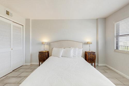 a white bedroom with a bed and two night stands at Emerald Surf 206 in Navarre