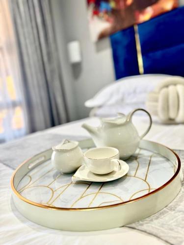 a tray with three tea sets on a bed at Glowti Event & Guest House in Centurion