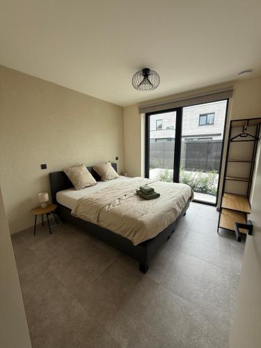 a bedroom with a large bed and a large window at Maison Impression vakantiehuis in Middelkerke