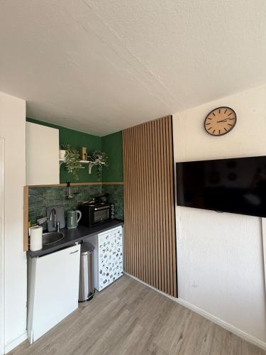 a small kitchen with a clock on the wall at Apartment Cozy Note für 2 in Bremerhaven