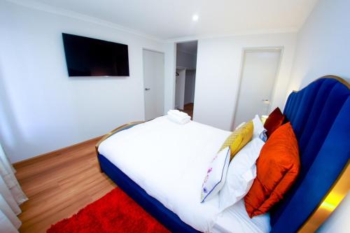 a bedroom with a large white bed with orange pillows at Urban Virgo Escape in Caversham