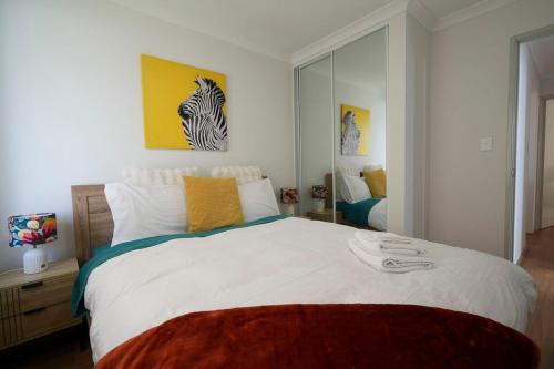 a bedroom with a large white bed and a mirror at Urban Virgo Escape in Caversham