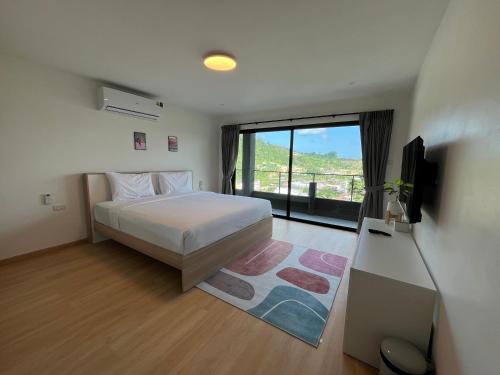 a bedroom with a bed and a tv and a window at Hill Bay Suites Hotel in Patong Beach