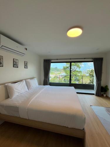a bedroom with a large white bed with a large window at Hill Bay Suites Hotel in Patong Beach
