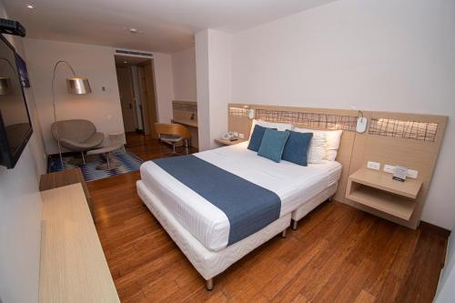 a bedroom with a large bed with blue pillows at Cosmos Pacifico Hotel in Buenaventura