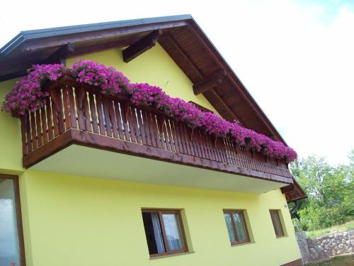 a yellow building with a balcony with purple flowers at House Mara in Korenica