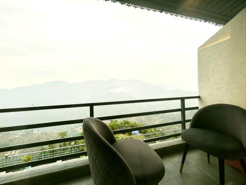 a room with two chairs and a large window at The Edge Retreat A Premium Property in Mussoorie