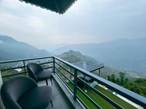 a balcony with two chairs and a view of mountains at The Edge Retreat A Premium Property in Mussoorie