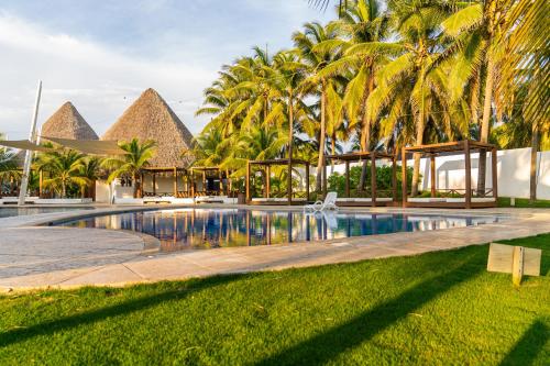 a resort swimming pool with palm trees in the background at Villas La Mar in Monterrico
