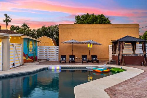 a pool with chairs and umbrellas next to a building at Relaxing Casita - Pool - Spa - Prime Location in Phoenix
