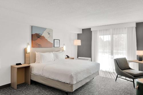 a hotel room with a bed and a chair at Spark By Hilton Toronto Markham in Markham