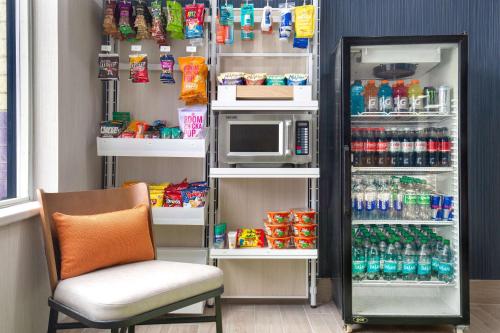 a refrigerator with a microwave and a chair in a room at Spark by Hilton Brockville in Brockville