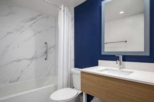 a bathroom with a toilet and a sink and a tub at Spark by Hilton Brockville in Brockville