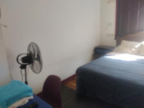 a room with a bed and a desk with a fan at hostel plaza brasil in Santiago