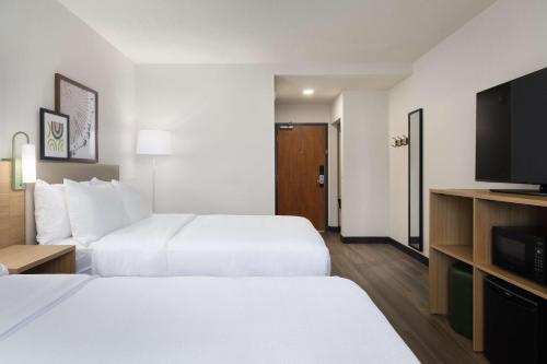 a hotel room with two beds and a flat screen tv at Spark By Hilton Guelph in Guelph