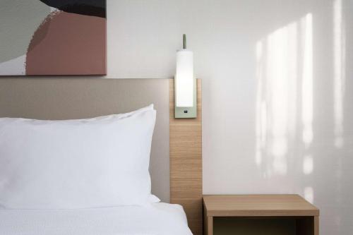 a bedroom with a white bed and a nightstand with a lamp at Spark By Hilton Guelph in Guelph