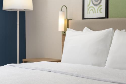 a bed with white sheets and pillows next to a lamp at Spark By Hilton Woodstock in Woodstock