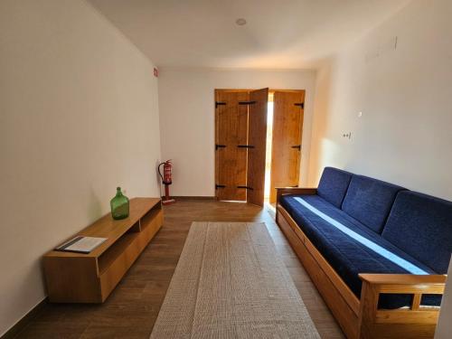 a living room with a blue couch and a table at Herdadinha in Vimieiro