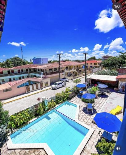 Una vista aérea de una piscina con sombrillas. en Novo hotel Maracaípe, en Porto de Galinhas