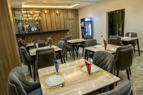 un restaurante con mesas y sillas y una mujer sentada en una mesa en Motion Hotel and Suites, en Uyo