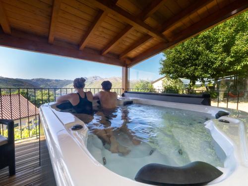 Zwei Personen sitzen in einem Whirlpool auf einer Terrasse in der Unterkunft Assento Gerês - Grand Eco-Retreat - jacuzzi views in Lindoso