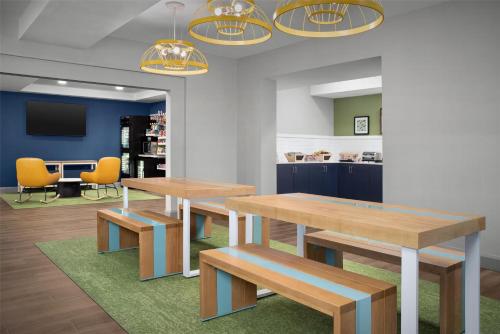 two wooden tables and benches in a room at Spark By Hilton Tucson Airport in Tucson