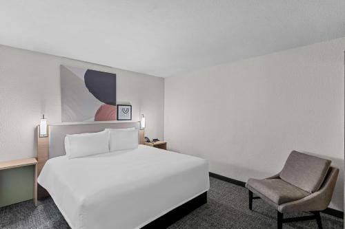 a hotel room with a white bed and a chair at Spark by Hilton Phoenix-Glendale-Peoria in Glendale
