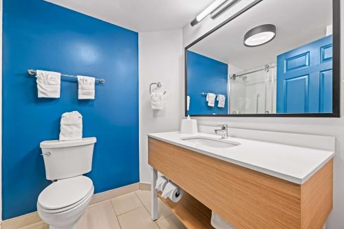 a bathroom with a white toilet and a blue wall at Spark by Hilton Tuscaloosa University in Tuscaloosa