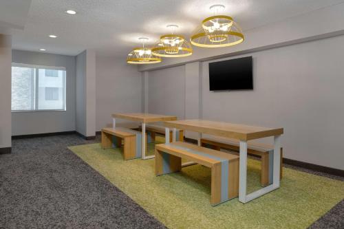 a conference room with two tables and a tv at Spark by Hilton Bentonville in Bentonville
