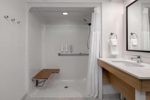 a white bathroom with a shower and a sink at Spark by Hilton Bentonville in Bentonville