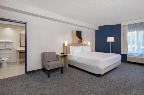 a hotel room with a bed and a chair at Spark by Hilton Bentonville in Bentonville