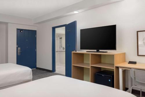 a hotel room with a bed and a television at Spark by Hilton Bentonville in Bentonville
