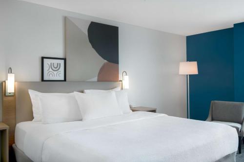 a hotel room with a white bed and a chair at Spark by Hilton Montgomery EastChase in Montgomery