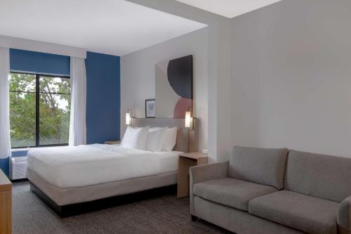 a hotel room with a bed and a couch at Spark by Hilton Montgomery EastChase in Montgomery