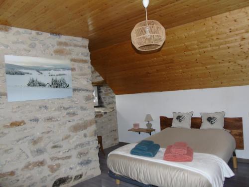a bedroom with a bed and a stone wall at LA LONGÈRE - Chambre Aubrac 