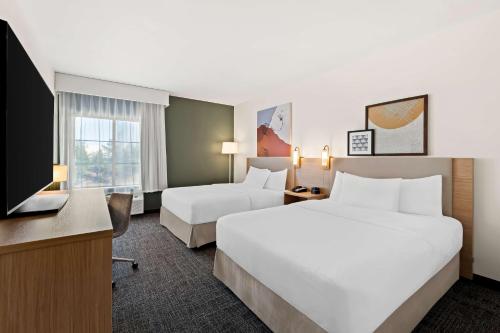 a hotel room with two beds and a flat screen tv at Spark by Hilton Little Rock West in Little Rock