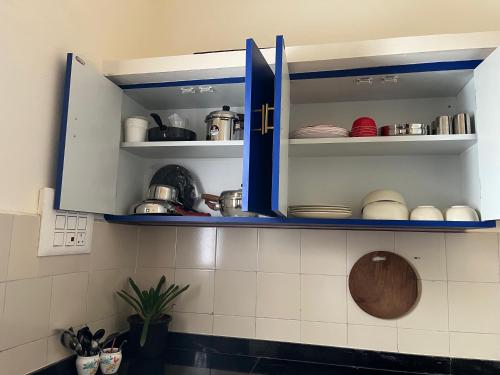 a kitchen with blue cabinets with dishes in it at MyYearlyStay in Udupi - Colonial in Udupi