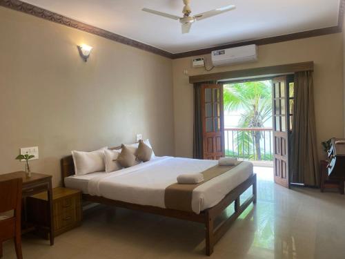 a bedroom with a large bed and a sliding glass door at Ashvem Beach inn in Mandrem