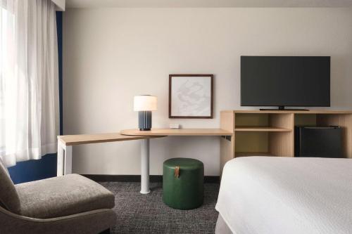 a hotel room with a desk with a tv and a chair at Spark By Hilton Mystic Groton in Mystic