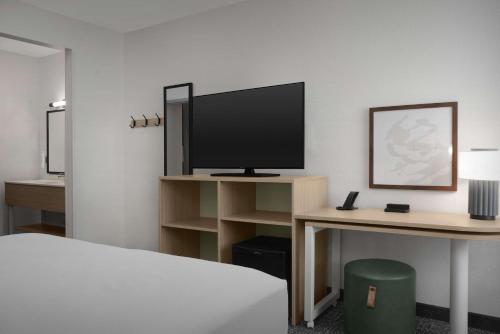 a room with a bed and a desk with a television at Spark by Hilton Miami Doral in Miami