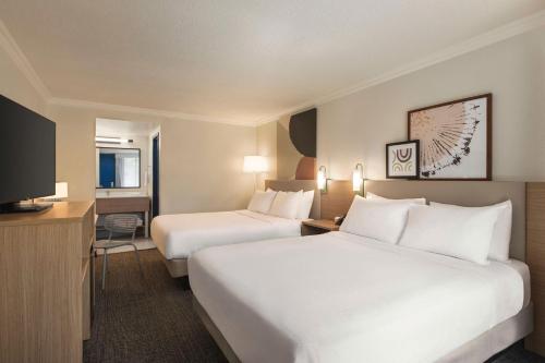 a hotel room with two beds and a television at Spark by Hilton Sarasota Siesta Key Gateway in Sarasota