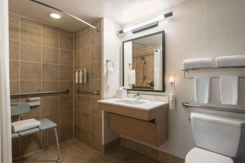 a bathroom with a sink and a toilet and a mirror at Spark by Hilton Sarasota Siesta Key Gateway in Sarasota