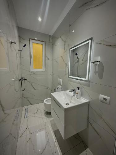 a white bathroom with a sink and a shower at Selami GuestHouse in Peshkopi
